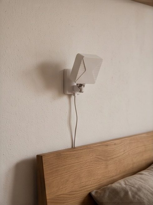 Symbolbild: Sturzsensor an der Wand über dem Kopfteil eines Holzbetts