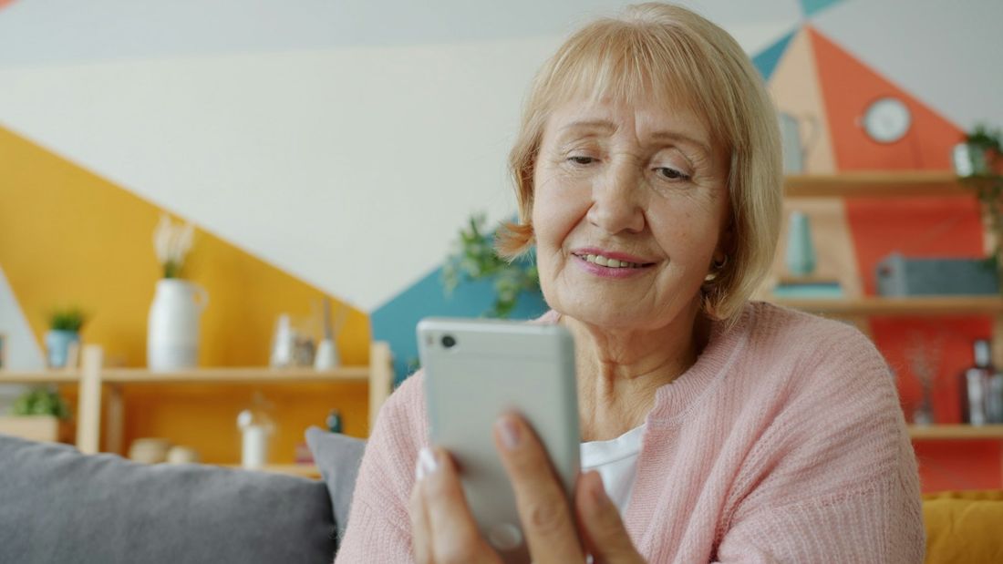 Ältere Frau lächelt beim Blick auf ihr Smartphone